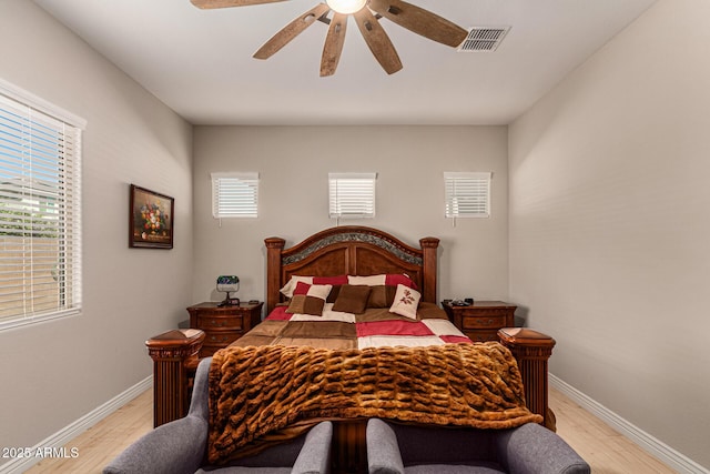 bedroom with ceiling fan, light hardwood / wood-style floors, and multiple windows