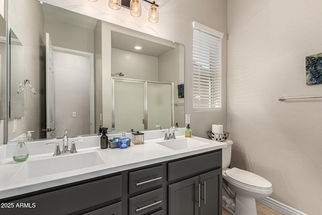 bathroom featuring vanity, a shower with shower door, and toilet