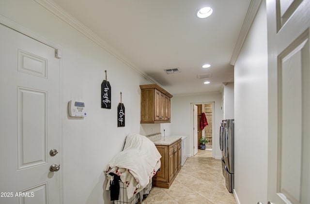 washroom with cabinets, light tile patterned floors, washing machine and dryer, and ornamental molding