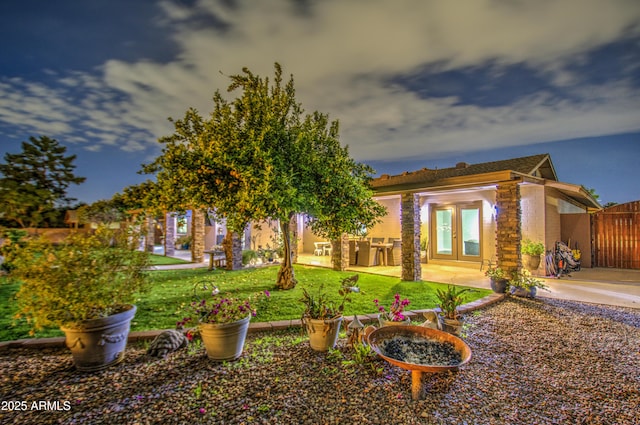 yard at dusk with a patio and french doors