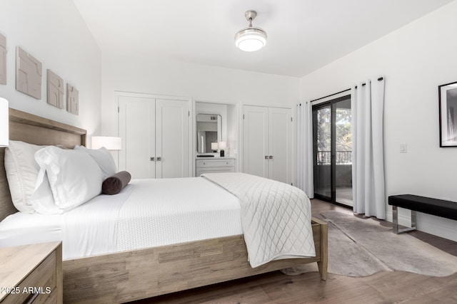 bedroom featuring multiple closets, hardwood / wood-style flooring, and access to outside