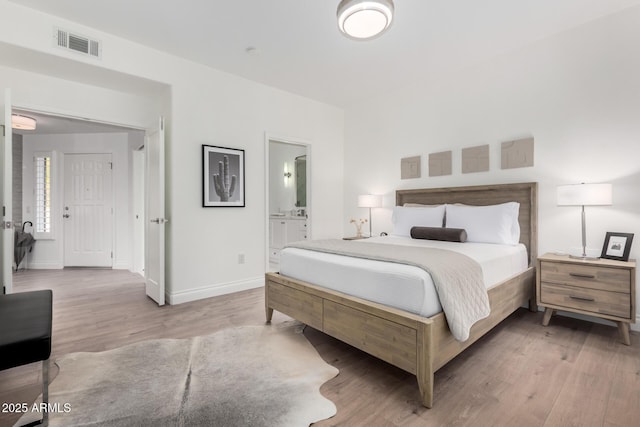 bedroom with connected bathroom and hardwood / wood-style floors