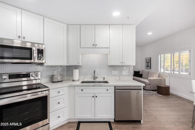 kitchen featuring white cabinetry, stainless steel appliances, sink, and backsplash