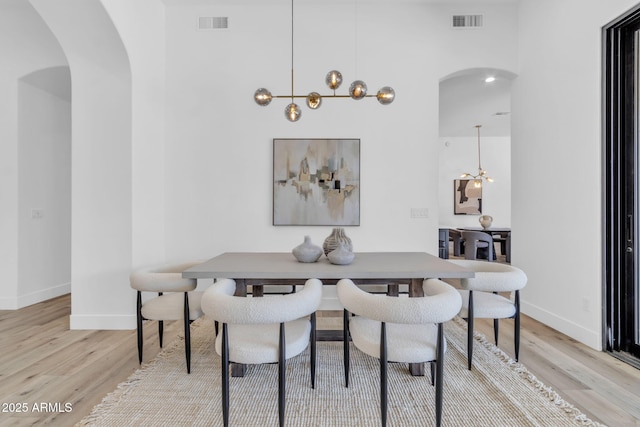 dining area featuring visible vents, arched walkways, and light wood-style flooring