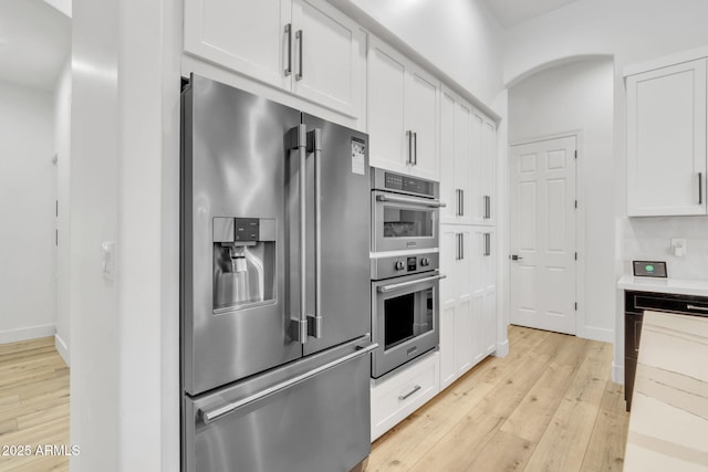 kitchen featuring stainless steel appliances, light countertops, white cabinetry, and light wood-style floors