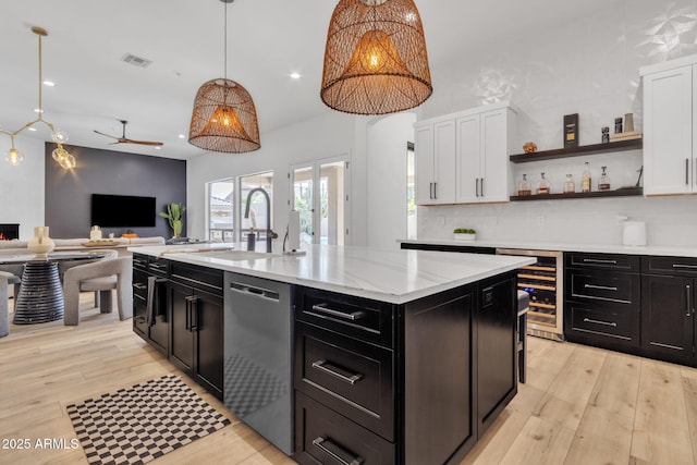 kitchen with light wood-style flooring, white cabinets, a sink, dark cabinetry, and dishwasher