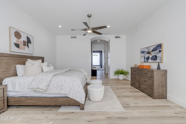 bedroom with arched walkways, light wood finished floors, visible vents, and recessed lighting