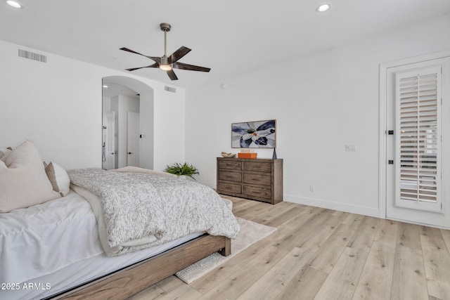 bedroom with arched walkways, light wood-type flooring, visible vents, and recessed lighting