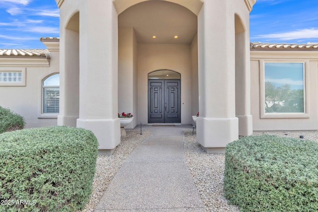 entrance to property with a tiled roof and stucco siding