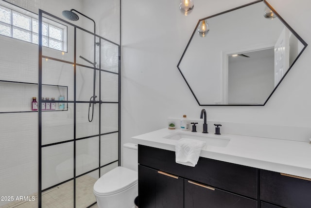 full bath featuring tiled shower, vanity, and toilet