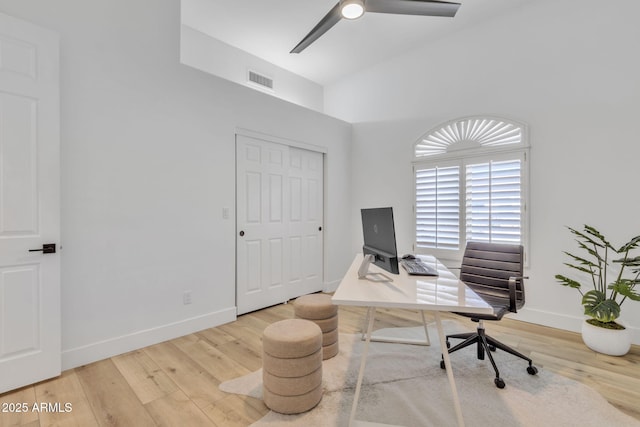 office space featuring lofted ceiling, a ceiling fan, visible vents, baseboards, and light wood-type flooring