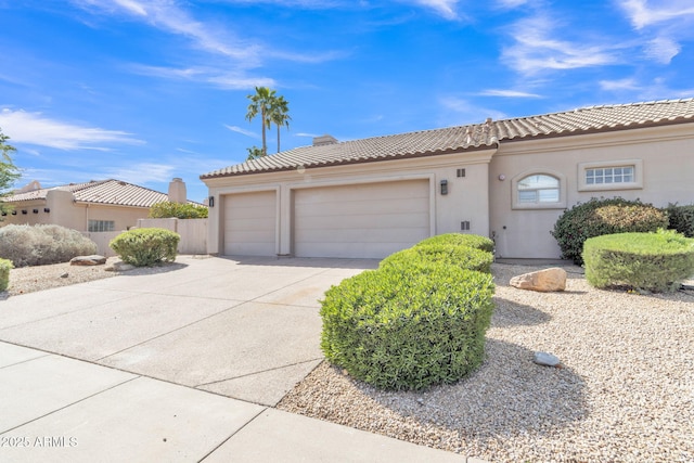 mediterranean / spanish-style house with concrete driveway, a tiled roof, an attached garage, and stucco siding