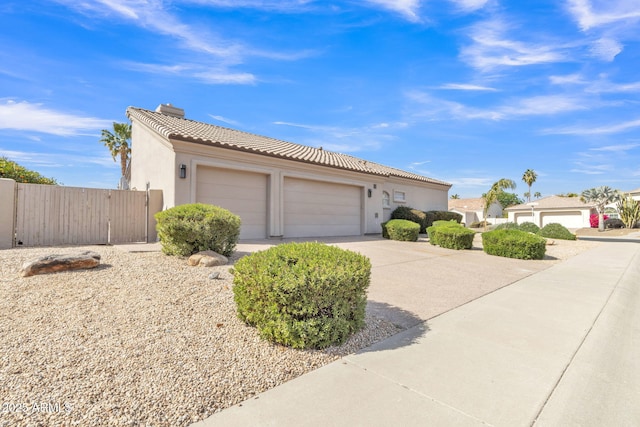 view of front of property with a chimney, stucco siding, an attached garage, driveway, and a tiled roof