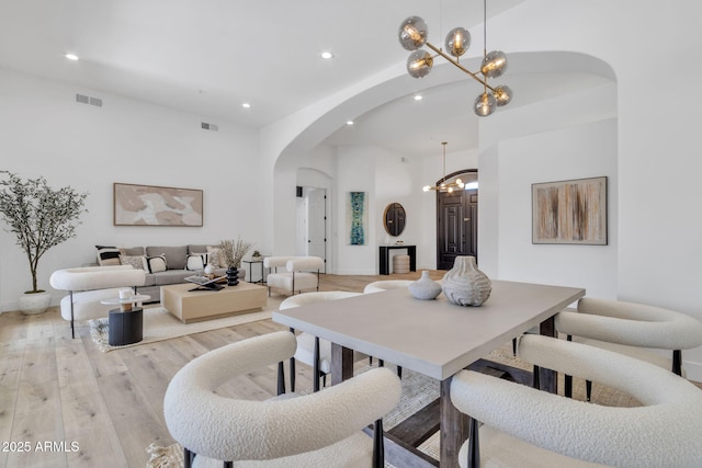 dining room featuring arched walkways, recessed lighting, visible vents, and light wood-style floors