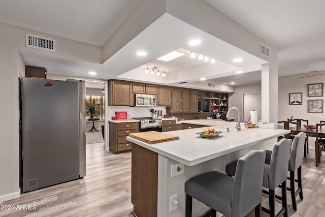 kitchen featuring appliances with stainless steel finishes, light hardwood / wood-style flooring, a breakfast bar area, and sink