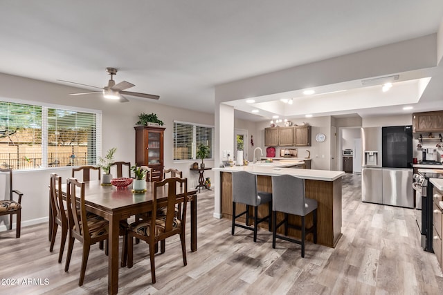 dining room with ceiling fan, sink, and light hardwood / wood-style flooring