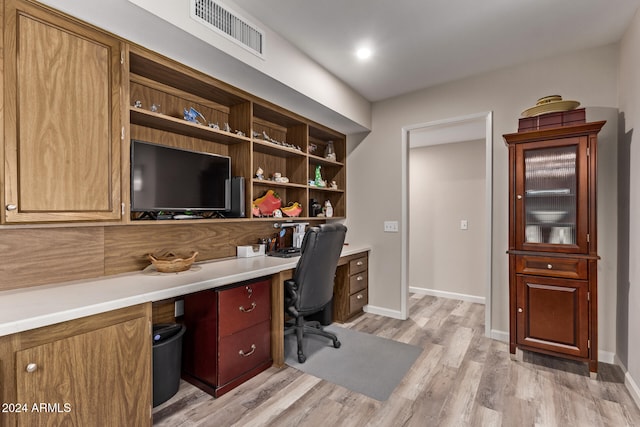 home office featuring light wood-type flooring and built in desk