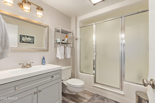 full bathroom featuring hardwood / wood-style floors, vanity, toilet, and combined bath / shower with glass door