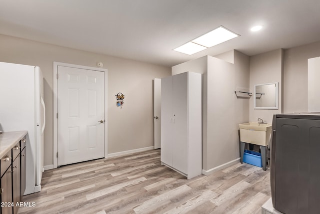 clothes washing area featuring washer / clothes dryer, light hardwood / wood-style flooring, and sink