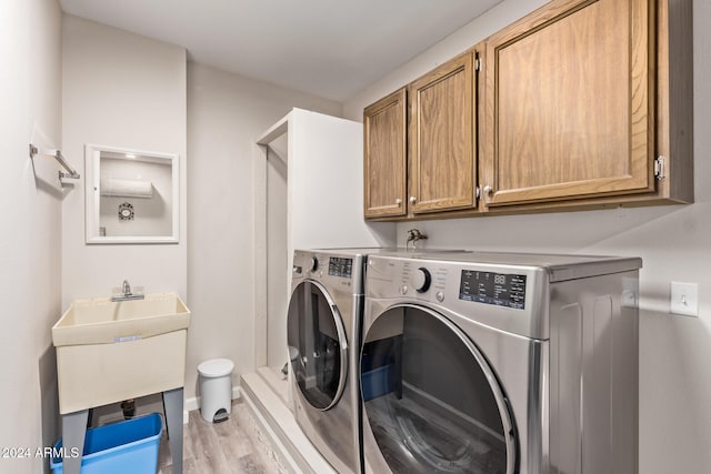 clothes washing area featuring washing machine and dryer, cabinets, and light hardwood / wood-style floors