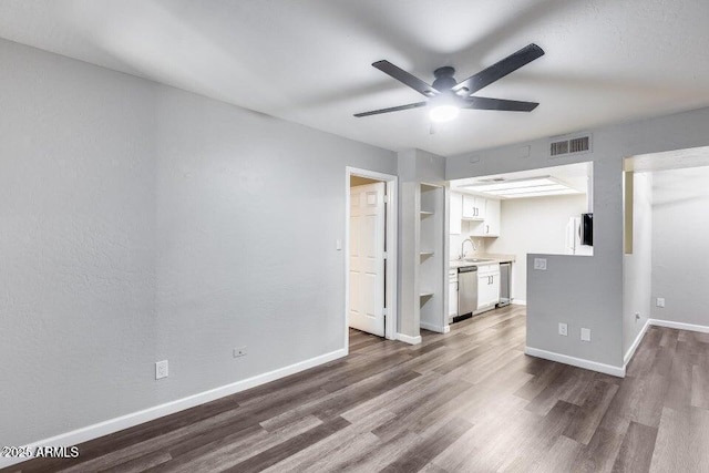 unfurnished living room with built in shelves, dark hardwood / wood-style flooring, ceiling fan, and sink