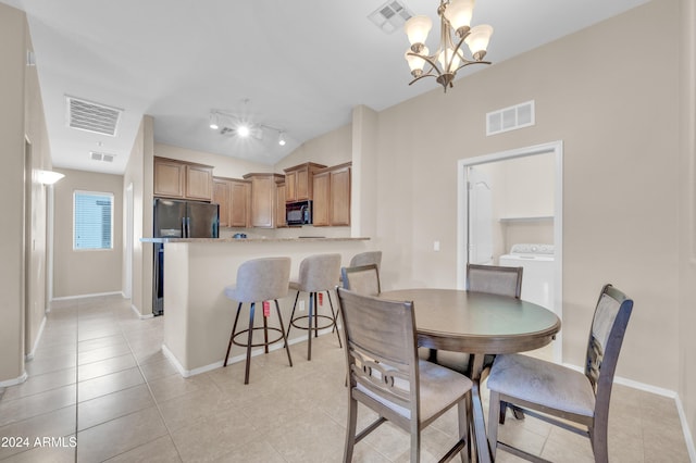 tiled dining room with a chandelier, vaulted ceiling, and washer / dryer