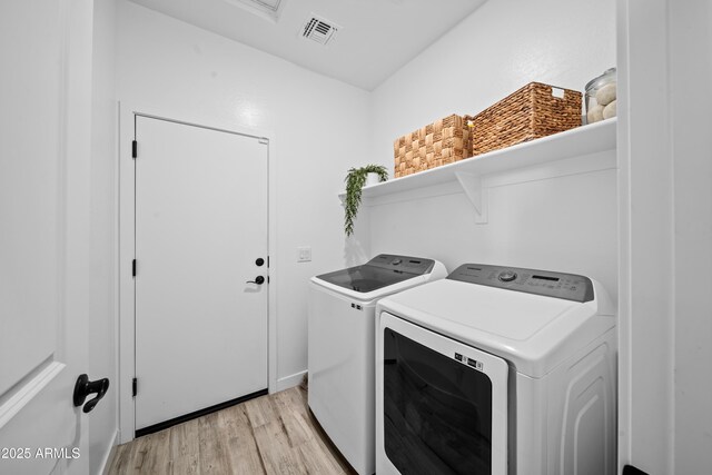 clothes washing area with washer and dryer, laundry area, visible vents, and light wood-style flooring