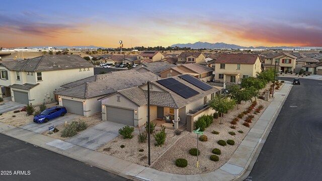 aerial view at dusk featuring a mountain view and a residential view