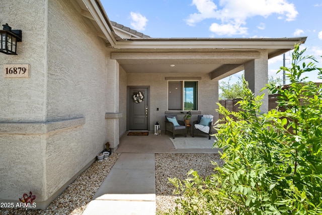 view of exterior entry with fence and stucco siding