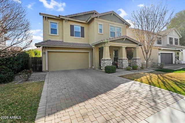 craftsman-style house featuring a front lawn, a tile roof, stucco siding, decorative driveway, and a garage