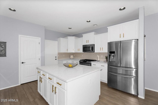 kitchen with tasteful backsplash, a kitchen island, dark wood-type flooring, appliances with stainless steel finishes, and white cabinets