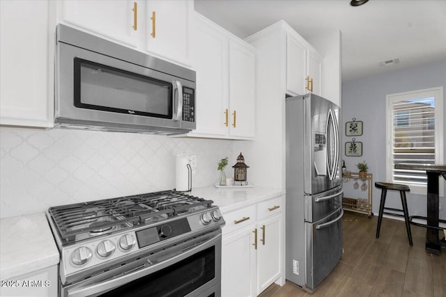 kitchen featuring tasteful backsplash, appliances with stainless steel finishes, wood finished floors, and white cabinetry