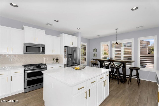 kitchen with decorative backsplash, wood finished floors, visible vents, and stainless steel appliances