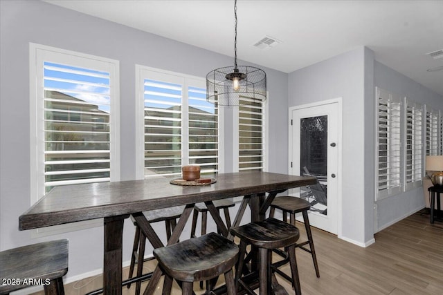 dining room featuring visible vents, a healthy amount of sunlight, and wood finished floors