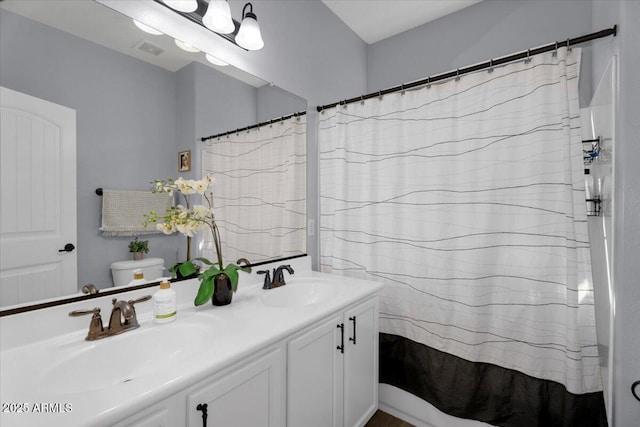 full bath with double vanity, toilet, visible vents, and a sink