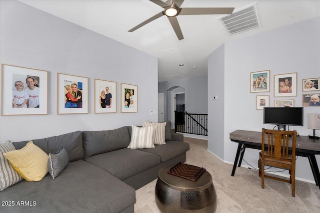 carpeted living room featuring visible vents, arched walkways, baseboards, and ceiling fan