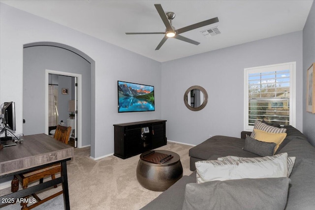 living area featuring visible vents, light carpet, arched walkways, baseboards, and ceiling fan