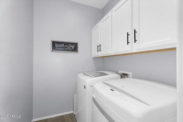 washroom featuring baseboards, cabinet space, independent washer and dryer, and wood finished floors