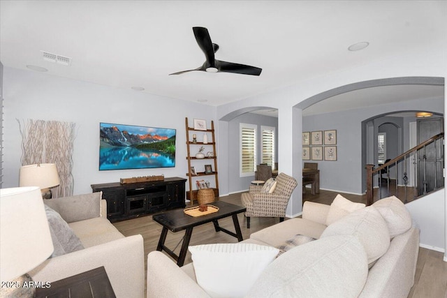 living area featuring wood finished floors, arched walkways, visible vents, and ceiling fan