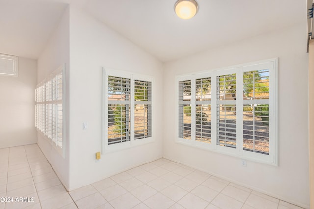 tiled empty room featuring lofted ceiling