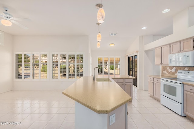 kitchen featuring plenty of natural light, white appliances, hanging light fixtures, and a kitchen island with sink