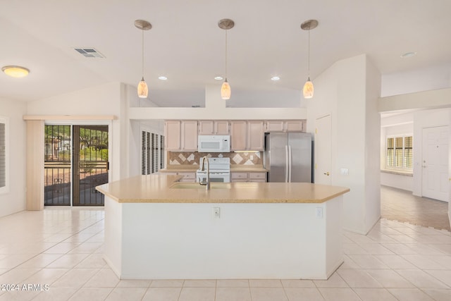 kitchen with hanging light fixtures, white appliances, and a center island with sink