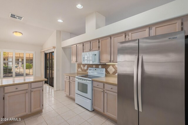 kitchen featuring vaulted ceiling, backsplash, white appliances, light brown cabinets, and light tile patterned floors