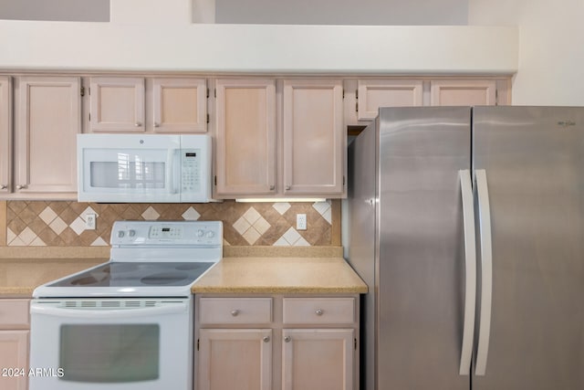 kitchen featuring light brown cabinetry, tasteful backsplash, and white appliances