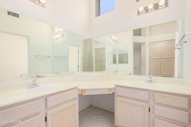 bathroom with vanity, a towering ceiling, and tile patterned flooring