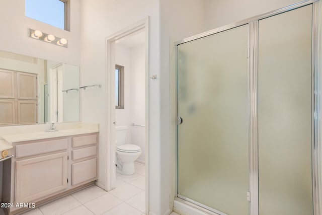 bathroom featuring tile patterned flooring, a shower with door, toilet, and vanity