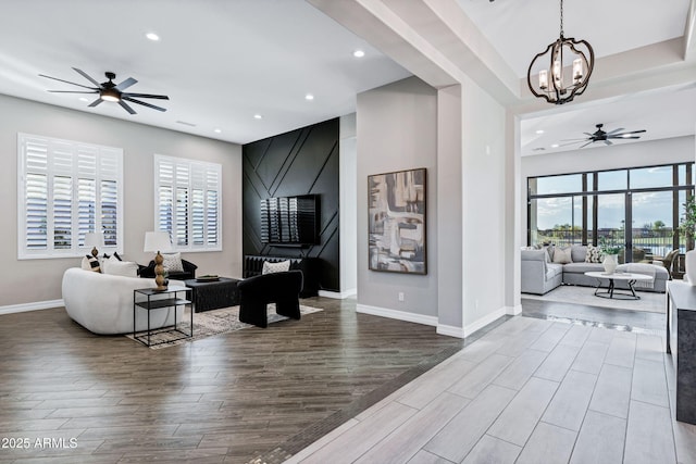 living area featuring ceiling fan with notable chandelier, wood finished floors, and a healthy amount of sunlight