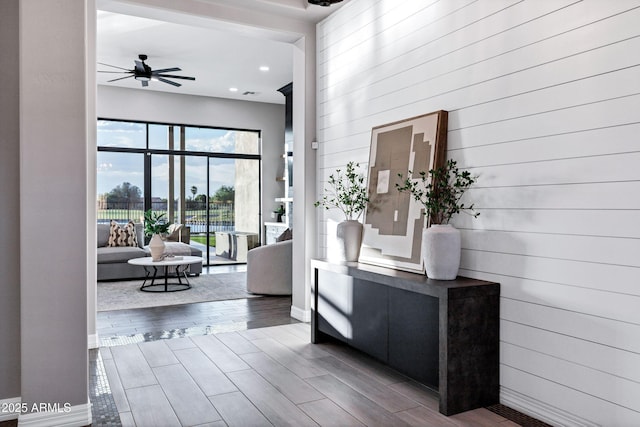 corridor with wooden walls, baseboards, recessed lighting, and wood finished floors
