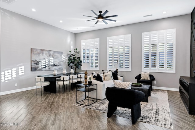 living room featuring baseboards, ceiling fan, visible vents, and a wealth of natural light