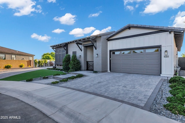 ranch-style home with an attached garage, decorative driveway, fence, and brick siding
